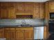 View of kitchen with wooden cabinets, tile backsplash, and stainless-steel sink at 1455 River Cove Rd, Social Circle, GA 30025