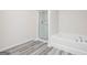 Bright bathroom features a glass enclosed shower and soaking tub with modern fixtures and wood-look flooring at 280 Limestone Circle, Conyers, GA 30013