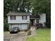 Split-level home with a two-car garage, wooden deck, stone porch and mature trees at 6884 Red Maple Ct, Rex, GA 30273