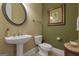 Powder room with a pedestal sink, round mirror, and decorative artwork at 185 Platinum Ridge Pt, Fayetteville, GA 30215