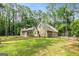 Rear view of home with fenced yard, surrounded by mature trees on a sunny lot at 215 Longwood Dr, Jonesboro, GA 30236