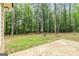Concrete patio overlooks back yard filled with mature hardwood trees and lush green grass at 215 Longwood Dr, Jonesboro, GA 30236
