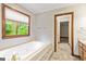 Bright bathroom features a large soaking tub under a window and an open doorway at 215 Longwood Dr, Jonesboro, GA 30236