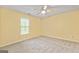 This carpeted bedroom includes a ceiling fan, window and light-yellow painted walls at 215 Longwood Dr, Jonesboro, GA 30236