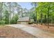 View of the home with a long driveway leading to a detached garage in a wooded setting at 215 Longwood Dr, Jonesboro, GA 30236
