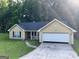 Inviting single Gathering home featuring an attached two-car garage and charming front yard at 8519 Glenwoods Dr, Riverdale, GA 30274