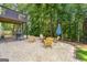 Relax in the backyard around the stone fire pit with wooden chairs and mature trees at 7505 Brookwood Way, Cumming, GA 30041