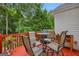 View of deck with red floors, metal table, and chairs and surrounded by lush greenery at 52 Cherub Ln, Sharpsburg, GA 30277