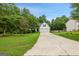 Traditional home with a long driveway and mature trees bordering the property and manicured lawn at 52 Cherub Ln, Sharpsburg, GA 30277