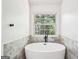 Modern bathroom featuring a soaking tub with matte black fixtures and a window overlooking a green landscape at 2580 Star Ln, Decatur, GA 30034