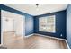 Cozy bedroom with blue walls, wood flooring, and a large window that allows natural light to flood in at 2580 Star Ln, Decatur, GA 30034