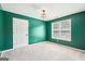 A bedroom featuring light-colored carpet, green walls, a geometric light fixture, and natural light at 2580 Star Ln, Decatur, GA 30034