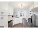 The kitchen features white cabinets, stainless appliances, and wood-look floors and a view into the dining and living areas at 2580 Star Ln, Decatur, GA 30034