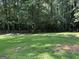 Fenced backyard with a large lush lawn and mature trees providing shade and privacy at 6875 Timberclair Ct, Lithonia, GA 30058