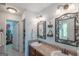 Well-lit bathroom with double sink vanity, decorative mirrors, and a door leading to a walk-in closet at 53 Denny Ln, Dallas, GA 30157