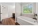 Bright bathroom showcasing a white tub with tile backsplash and nature view at 3865 Rifflepool Ct, Douglasville, GA 30135