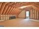 Unfinished attic with wooden beams, window, and plywood flooring offers potential for customization at 1709 Reese Rd, Sharpsburg, GA 30277