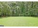 Green backyard featuring a well-maintained lawn and a backdrop of lush trees at 1709 Reese Rd, Sharpsburg, GA 30277