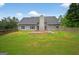 Charming backyard with lush green grass, fenced perimeter, and a gray house with a concrete patio at 65 Pecan Ln, Oxford, GA 30054