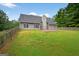 Lush backyard showcasing green grass and a gray house with a wood fence at 65 Pecan Ln, Oxford, GA 30054