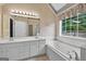Bathroom with double sinks, a bathtub, a shower, and a window to provide natural light at 65 Pecan Ln, Oxford, GA 30054