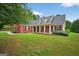 Charming red brick house boasts a covered front porch, classic shutters, and lush green lawn creating a warm, inviting curb appeal at 65 Pecan Ln, Oxford, GA 30054