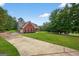 Red brick home with a long driveway, spacious lawn, and lush greenery in a serene setting under a clear, sunny sky at 65 Pecan Ln, Oxford, GA 30054
