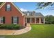 Close-up of a red brick home with a covered front porch, showcasing its well-maintained landscaping and inviting entrance at 65 Pecan Ln, Oxford, GA 30054
