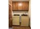 Laundry room area with washer, dryer, tile floors and wooden cabinets at 807 Oak Bridge Ln, Fayetteville, GA 30214