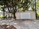 Home exterior with large mature trees, a gray house, metal garage, and concrete driveway at 6192 Collins Ne St, Covington, GA 30014