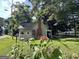 Charming exterior view of home with green lawn, mature trees, brick chimney, and sunflower in foreground at 6192 Collins Ne St, Covington, GA 30014