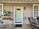 Charming covered front porch with comfortable seating and decorative plants near a light green door at 6192 Collins Ne St, Covington, GA 30014