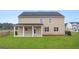 Large backyard featuring green grass, a covered patio, and exterior view of the tan colored house at 687 Edgar St # 83, Hampton, GA 30228