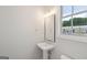 Bright powder room with a pedestal sink, mirror, and window offering natural light at 1100 Thomas St, Woodstock, GA 30188