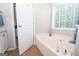 Bright bathroom boasts a soaking tub, tile floors, and a large window with blinds at 65 Cold Harbor Ct, Sharpsburg, GA 30277