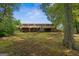 Expansive backyard featuring a brick home with a wooden balcony and staircase, all surrounded by lush greenery at 6674 Cowan Mill Rd, Winston, GA 30187