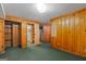 Finished basement with wood paneling, green carpet, closet, and an open doorway leading to other parts of the basement at 6674 Cowan Mill Rd, Winston, GA 30187