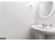 Pedestal sink with round mirror in a well-lit powder room at 308 Sarasota Ln, Locust Grove, GA 30248