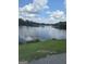 Peaceful lake view with lush green grass in the foreground and scattered clouds overhead at 2527 Amalfi Dr, Conyers, GA 30012