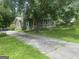 Long driveway flanked by trees leads to a cozy two-story house with a stone chimney at 212 Rockmart Rd, Villa Rica, GA 30180
