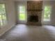 Bright living room featuring a stone fireplace, neutral paint, new carpet, and many windows at 212 Rockmart Rd, Villa Rica, GA 30180