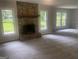 Bright living room featuring a stone fireplace, neutral paint, new carpet, and large windows at 212 Rockmart Rd, Villa Rica, GA 30180