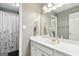 Bright bathroom featuring a white vanity, large mirror, updated fixtures and shower with floral curtain at 136 Barrington Grange Dr, Sharpsburg, GA 30277