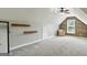 Bright bonus room with sloped ceiling, carpeted floors and unique wood accent wall for a cozy feel at 136 Barrington Grange Dr, Sharpsburg, GA 30277