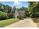 Side view of a home with a flag pole, driveway, lush trees, and landscaping at 136 Barrington Grange Dr, Sharpsburg, GA 30277