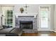 Cozy living room featuring a stone fireplace, hardwood floors, and large window for natural light at 136 Barrington Grange Dr, Sharpsburg, GA 30277