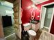 This bathroom features a toilet, sink, vanity with black countertop, and red wall at 610 Tower Rd, Peachtree City, GA 30269