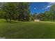 Lush green lawn with mature trees, featuring a view of the home and detached garage at 183 Inman Rd, Fayetteville, GA 30215