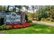 Welcoming entrance to Fairfield Plantation, featuring a stone sign, vibrant flowers, and a glimpse of the community at 1252 Heritage Dr, Villa Rica, GA 30180