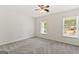 Neutral bedroom with two windows, a ceiling fan, and soft gray carpeting at 107 Edgewater Way, Peachtree City, GA 30269